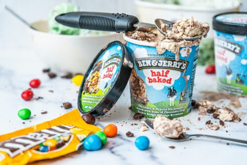 An open pint of Ben & Jerry's Half-Baked ice cream sits on a white marble countertop. 