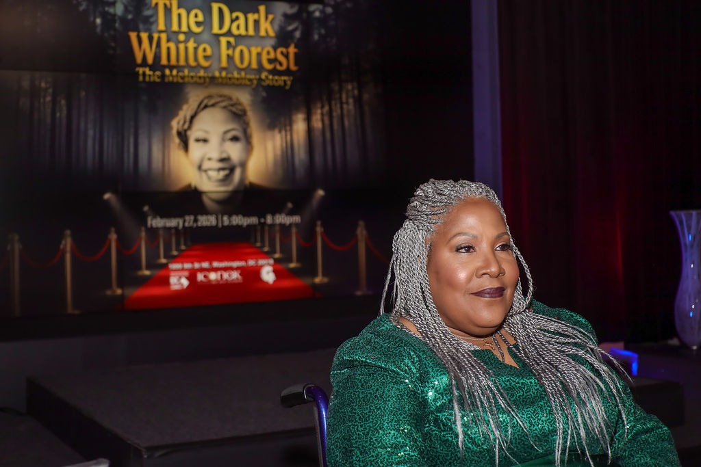 melody-1 Melody Mobley looks out at the audience. Behind her is a still image of her short film The Dark White Forest.